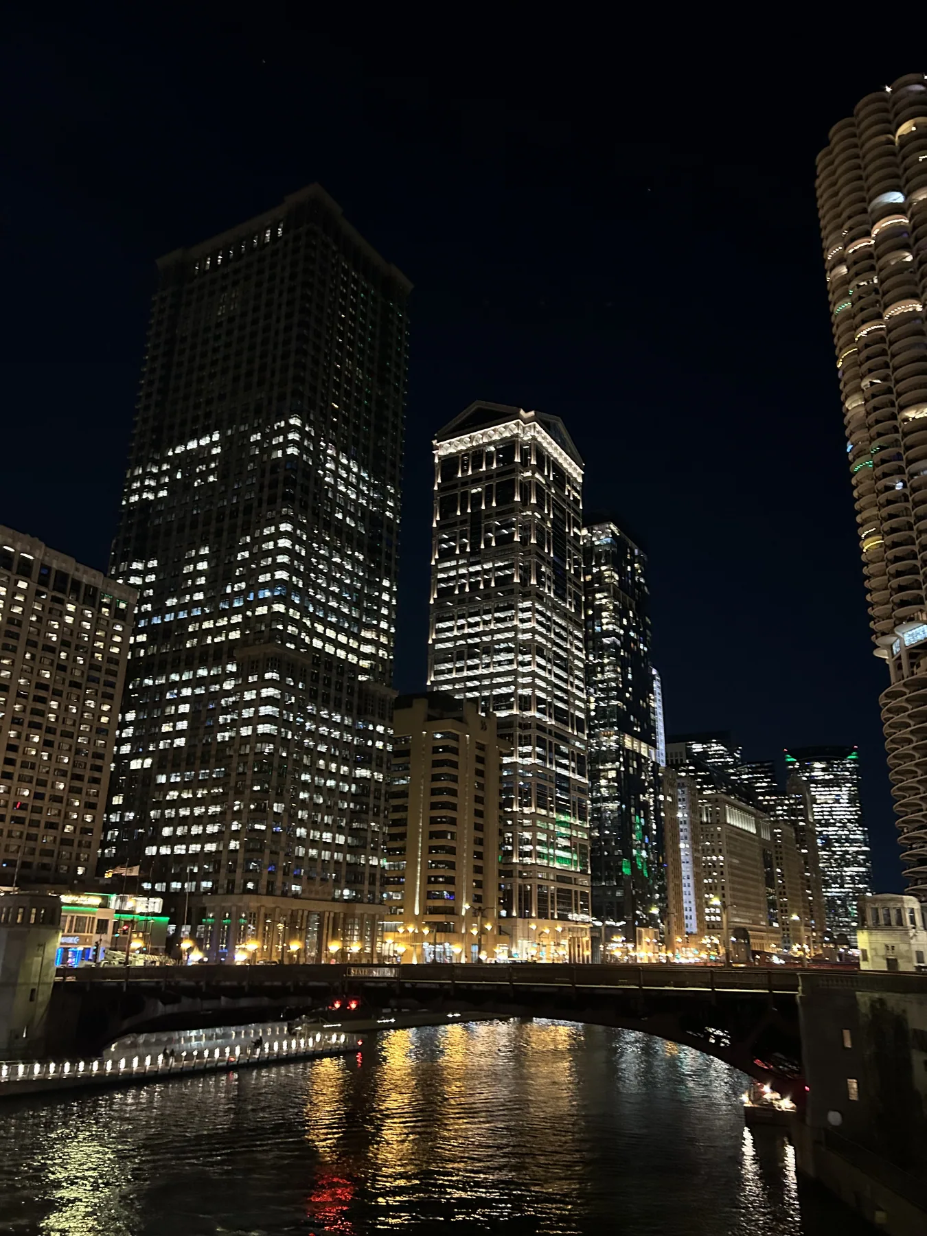 Downtown Chicago buildings and the river illuminated at night.